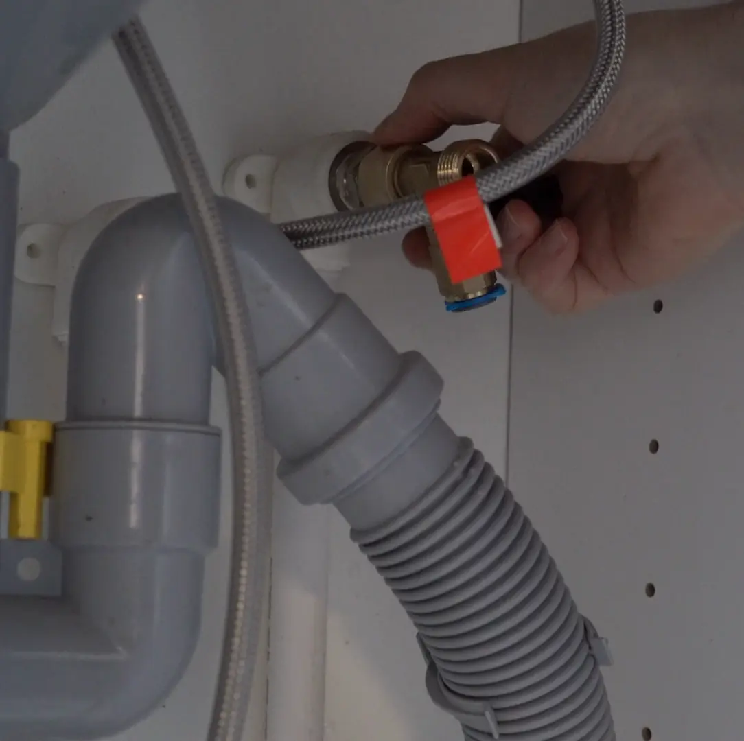 Hands fitting a pipe under a sink